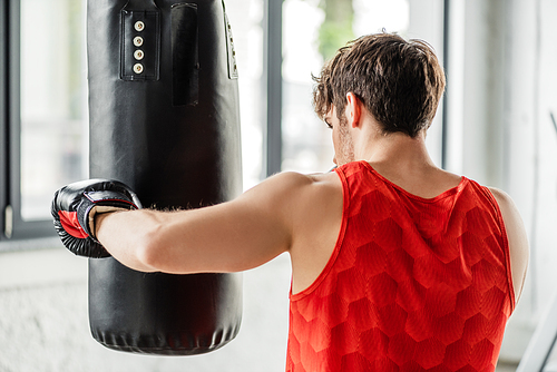 athletic man in sportswear and boxing gloves training with punching bag