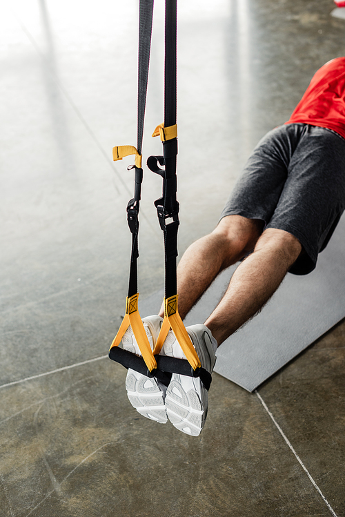 cropped view of sportsman exercising with elastics near fitness mat