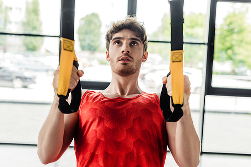 handsome and young sportsman working out with elastics in gym