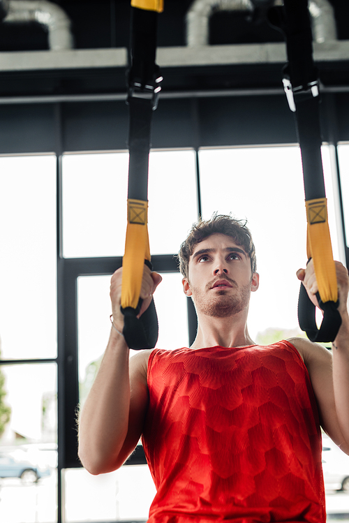 handsome and young sportsman exercising with elastics in gym