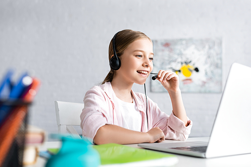 Selective focus of smiling kid using headset during online education