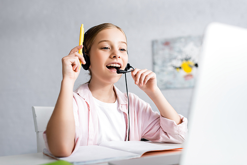 Selective focus of positive kid in headset having idea during online education at home