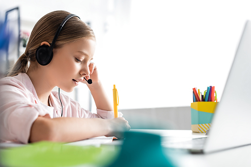 Selective focus of kid using headset during electronic learning at home