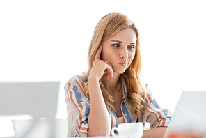 Selective focus of pensive woman looking at laptop with cup of tea