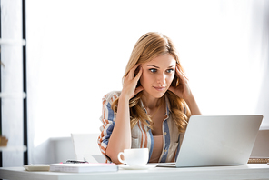 Selective focus of pensive woman looking at laptop
