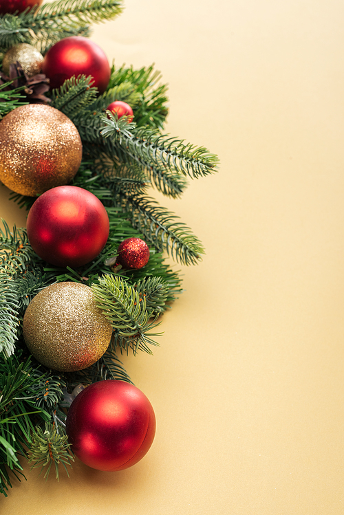 christmas tree branch with baubles on yellow background