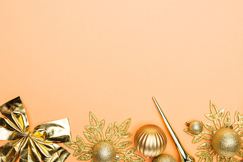 top view of golden Christmas decor on orange background with copy space