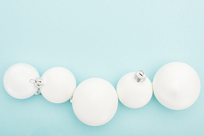 top view of white Christmas balls on light blue background with copy space