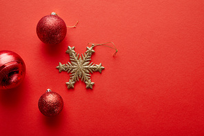 top view of shiny Christmas baubles and golden snowflake on red background
