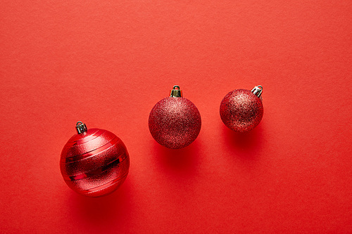 top view of shiny Christmas baubles on red background