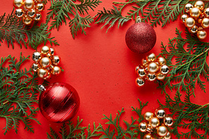 top view of shiny Christmas decoration and thuja on red background with copy space