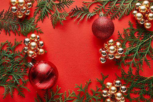 top view of shiny Christmas decoration and thuja on red background with copy space