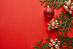 top view of shiny Christmas decoration and green thuja on red background with copy space