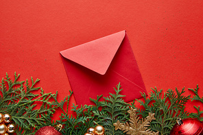 top view of shiny Christmas decoration, envelope and thuja on red background with copy space