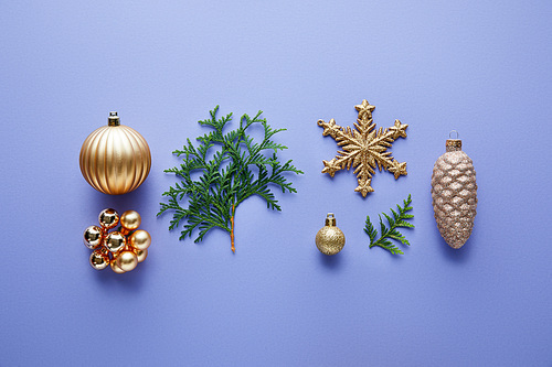 top view of shiny golden Christmas decoration, green thuja branches on blue background