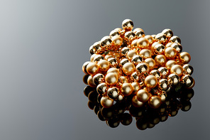 shiny golden Christmas decoration on grey background with reflection and copy space