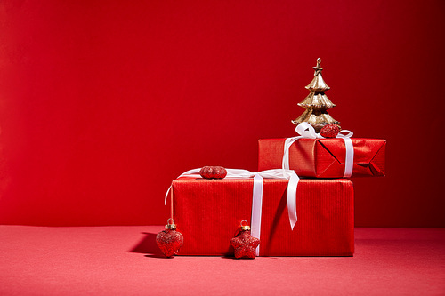 red gift boxes and decorative golden Christmas tree with baubles on red background