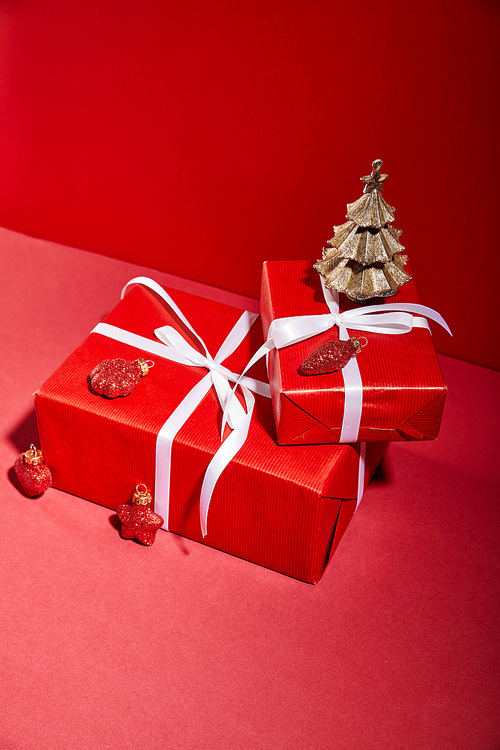 red gift boxes and decorative golden Christmas tree with baubles on red background