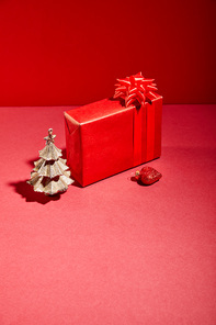 red gift box and decorative golden Christmas tree with bauble on red background