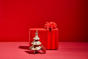 red gift box and decorative golden Christmas tree with bauble on red background
