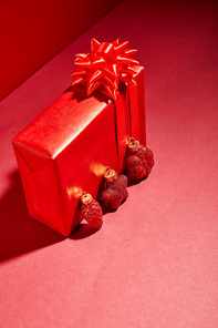 red wrapped festive gift box with baubles on red background