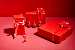 red wrapped festive gift boxes with ribbons and bows on red background