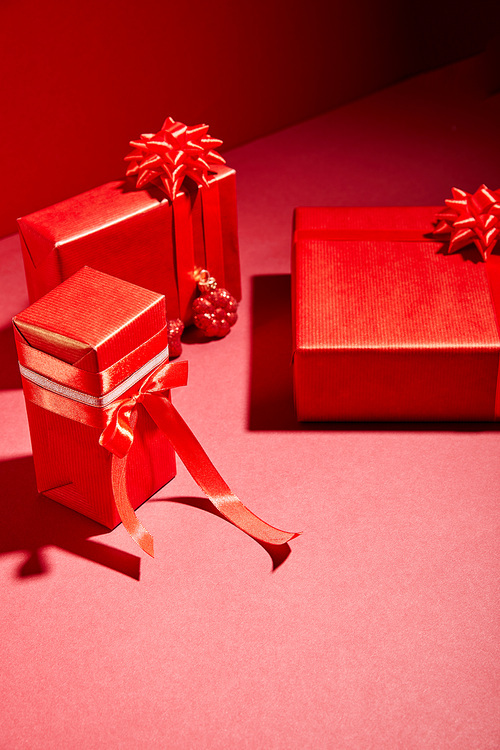 red wrapped festive gift boxes with ribbons and bows on red background