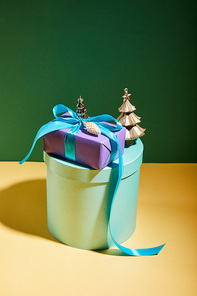 gift box with golden Christmas decoration on green and yellow background