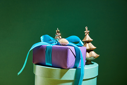 gift box with golden Christmas decoration on green background