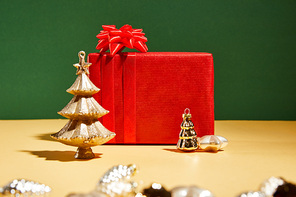 red gift box and decorative Christmas tree with golden baubles on green background