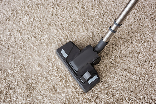 Top view of brush of vacuum cleaner on beige carpet