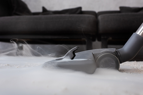 Low angle view of brush of vacuum cleaner with hot steam on carpet