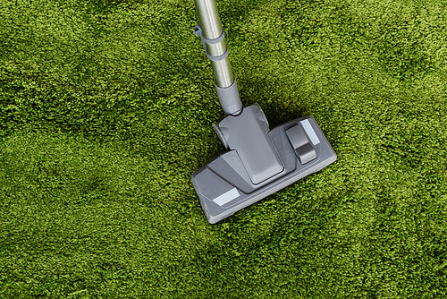 Top view of vacuum cleaner on green carpet