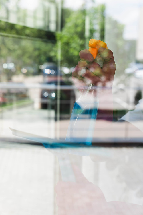 Selective focus of cleaner using detergent and squeegee handle while cleaning glass of window