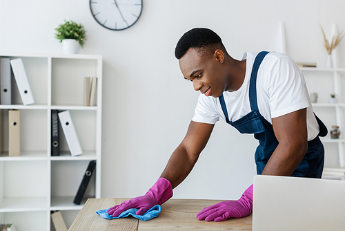 African american cleaner cleaning table while working in office