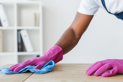 Cropped view of african american worker of cleaning service cleaning office table