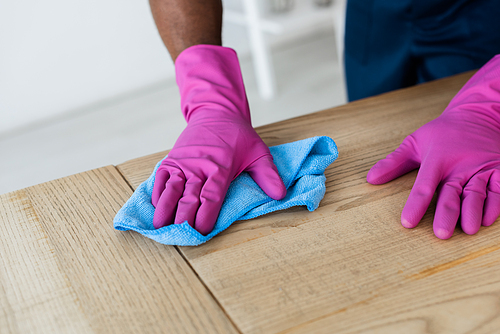 Cropped view of african american worker of commercial cleaning service cleaning table with rag in office