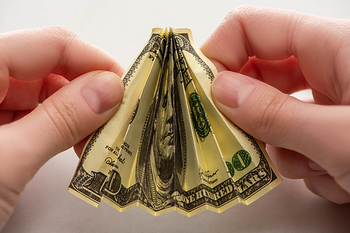 cropped view of woman holding crumpled dollar banknote in hands on white