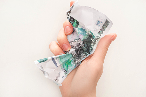 cropped view of woman holding crumpled ruble banknote isolated on white