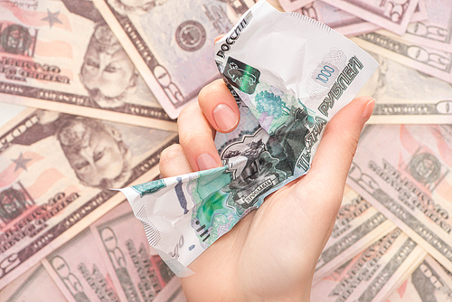 top view of woman holding crumpled ruble banknote near dollars