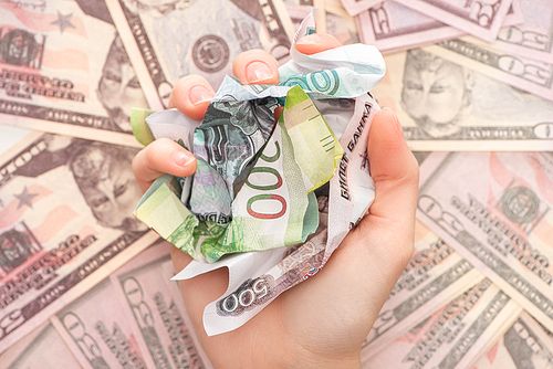 cropped view of woman holding crumpled ruble banknotes near dollars