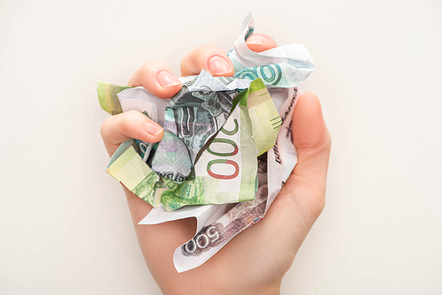 cropped view of woman holding crumpled ruble banknotes isolated on white