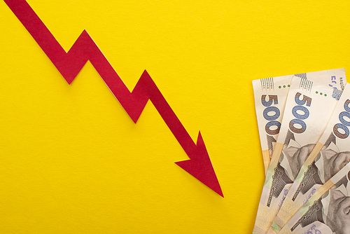 top view of crisis graph near ukrainian hryvnia banknotes isolated on yellow