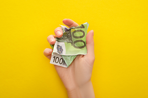 cropped view of woman holding crumpled euro banknote isolated on yellow