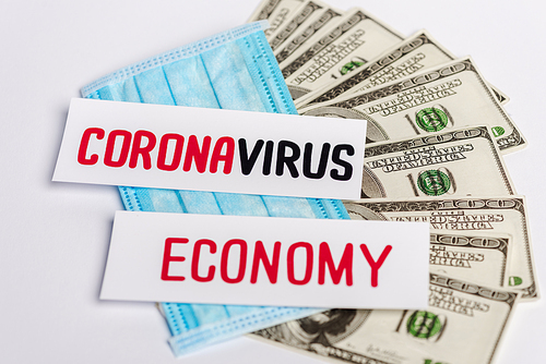 dollar banknotes, medical mask and coronavirus and economy cards on white background