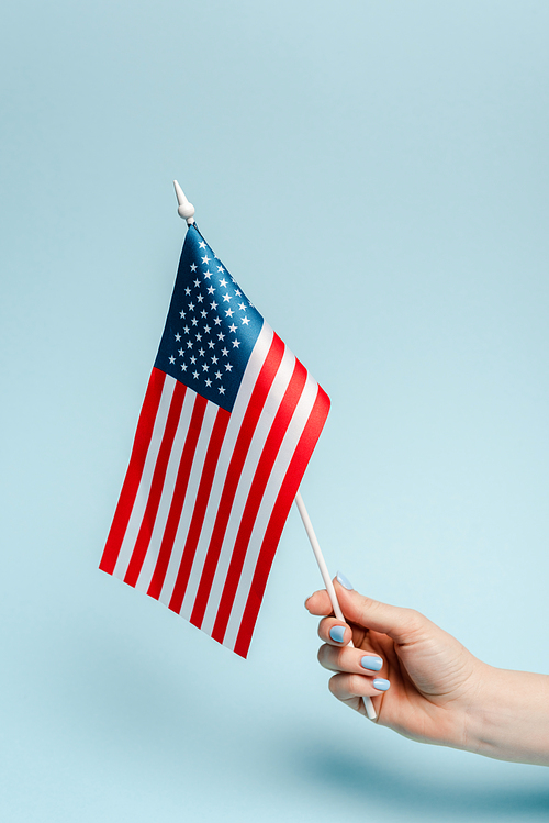 cropped view of woman holding american flag on blue background, coronavirus concept