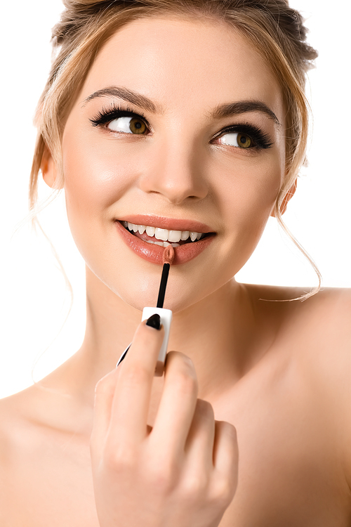 smiling naked beautiful blonde woman with makeup and black nails applying beige lip gloss isolated on white