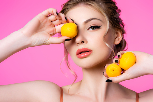 elegant beautiful blonde woman holding apricots isolated on pink