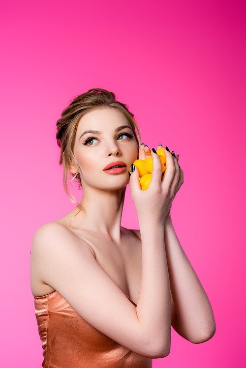 dreamy elegant beautiful blonde woman in silk dress holding ripe apricots isolated on pink
