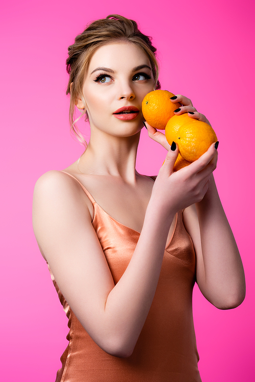 elegant beautiful blonde woman holding ripe oranges isolated on pink